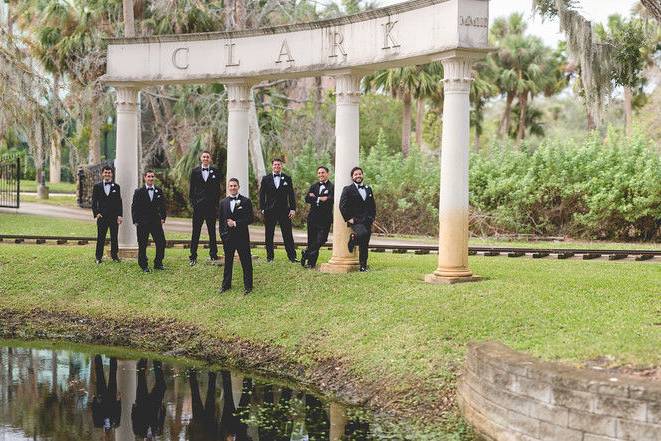 Groomsmen on lakeside by monument arch