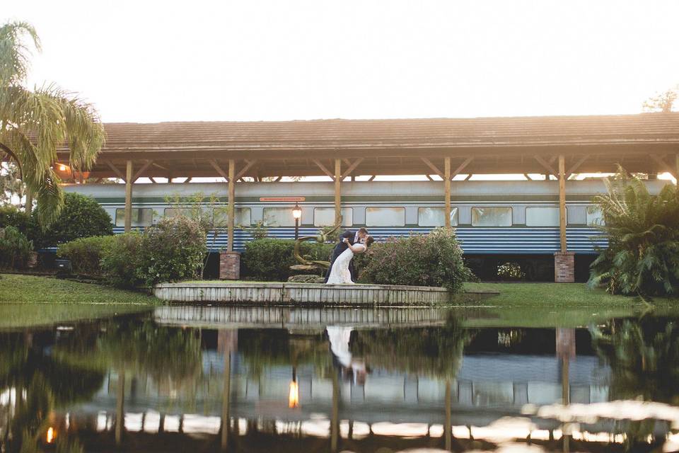 Couple on edge of lake in front of train at dusk