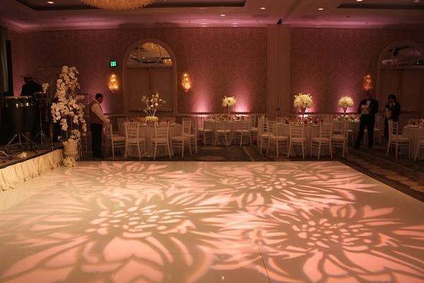 Floral patterns on the dance floor with blush pink uplights to complement
