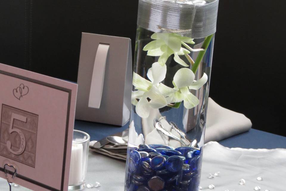 Floating candle in water with orchid and colored stones to match decor and silver ribbon.  Assigned seating.