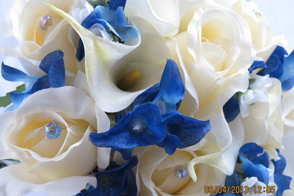 Life Touch silk cream roses with crystals, and Life Touch silk blue bonnetts with Calla lillies al hand tied and a special surprise for each of the girls..an engraved charm from the bride attached for them as a memento.   Cruise Wedding so they went with silk as no live flowers can be  taken onboard.
