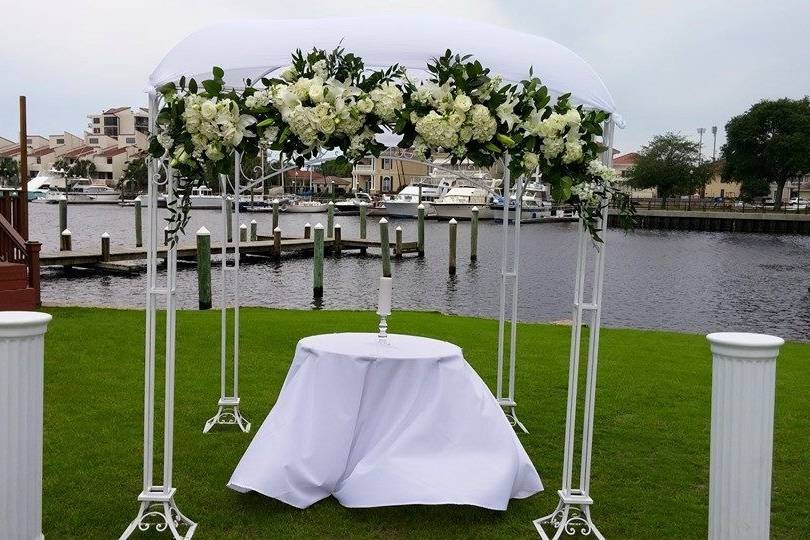 White metal arbor with chuppah and flowers