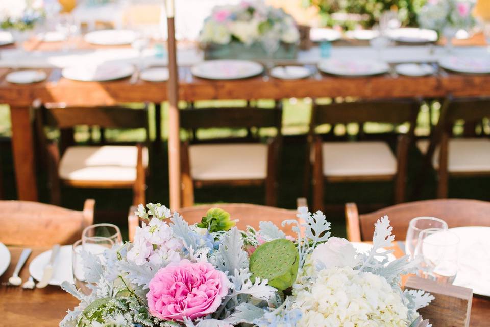 Centerpieces of rustic teal boxes overflowing with premium flowers. Containers available for rent.