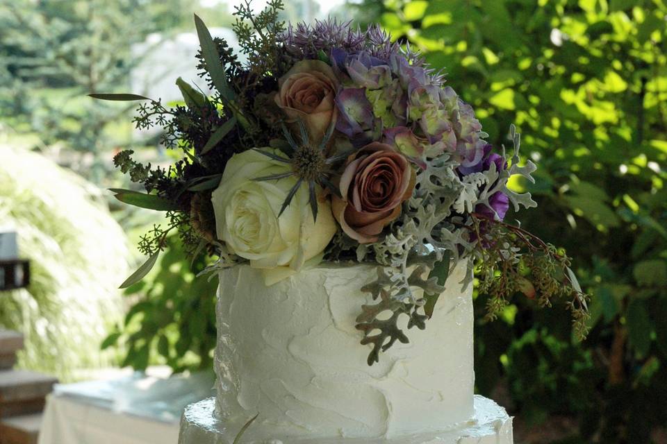 A rustic buttercream finish wedding cake, adorned with fresh flowers.  Elegant and can be formal or informal.