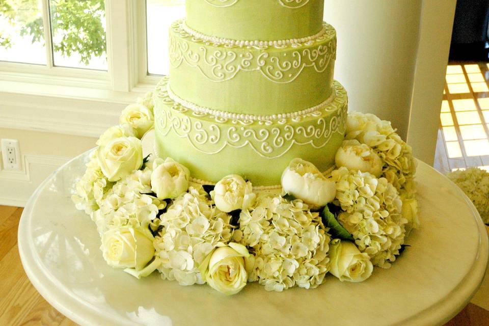 Mint buttercream wedding cake with scrolls and fresh hydrangeas, peonies and roses