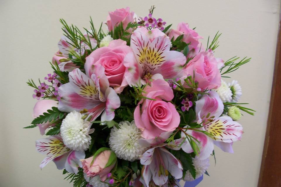 Sweet nosegay of spray roses, alstroemeria lilies and button poms accented with pink wax flower.