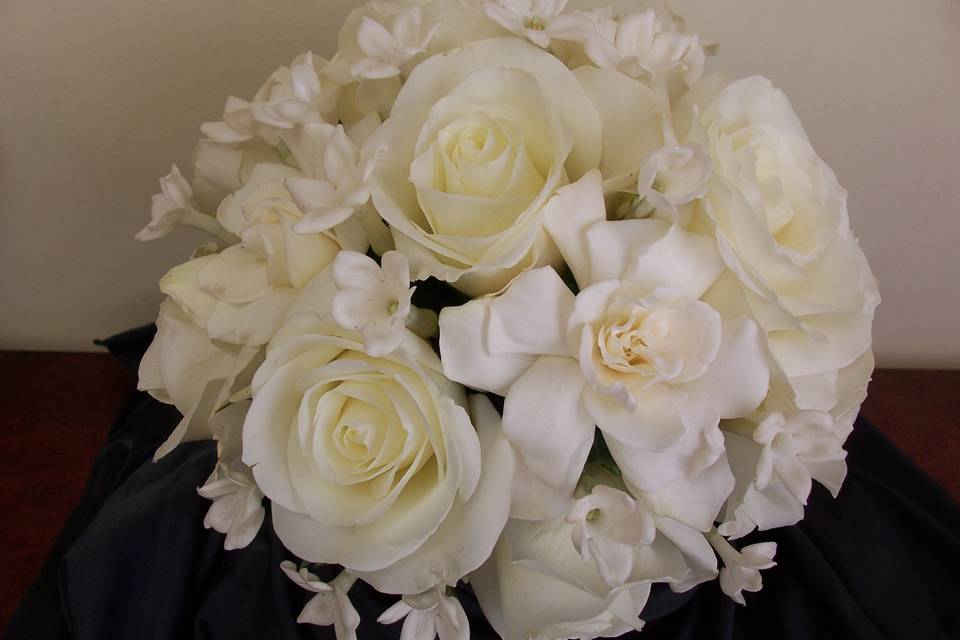 White roses, gardenias and stephanotis in a hand tied bouquet.