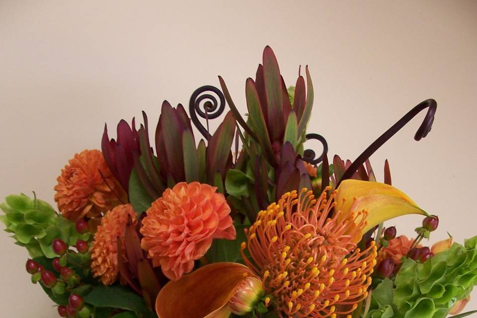 My favorite, the picture doesn't do it justice!  Pincushion protea, mango calla lilies, uhle, Bells of Ireland, leucadendron, dahlias and hypericum with a stem wrap of chocolate satin ribbon and diamante pins.  Lots of texture and interest!