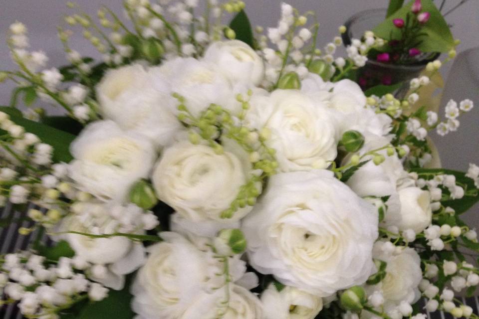 White ranunculus with Lily of the Valley in a hand tied bouquet.