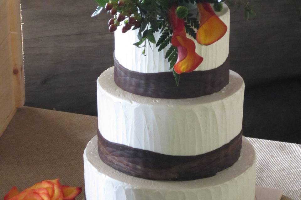 Calla lilies, roses, hypericum and button poms decorate the  cake.
