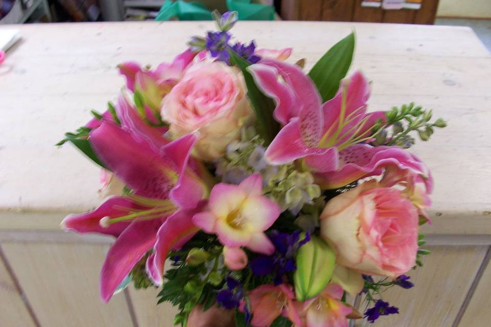 Pink roses, oriental lilies and freesia in a hand tied clutch bouquet.