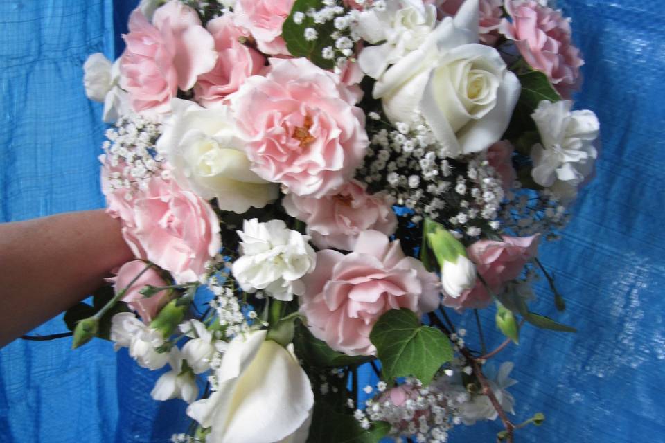 Traditional cascading bouquet of white roses, pink and white carnations with baby's breath.