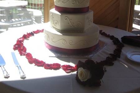 Round & Octogon layered buttercream cake with scroll work, silver dragees, burgundy ribbon and red roses.