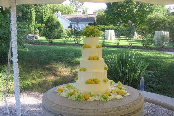 5 tier buttercream cake with vertical stripes, swiss dots, lemons and hydrangeas.