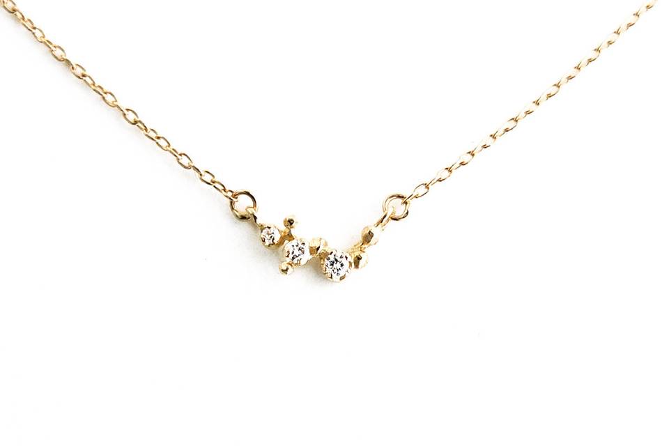 This charming necklace is detailed by hand from N+A New York. Three diamonds totaling .0374 carats are set in clustered beads of 14 karat yellow gold. The cluster measures 3/8