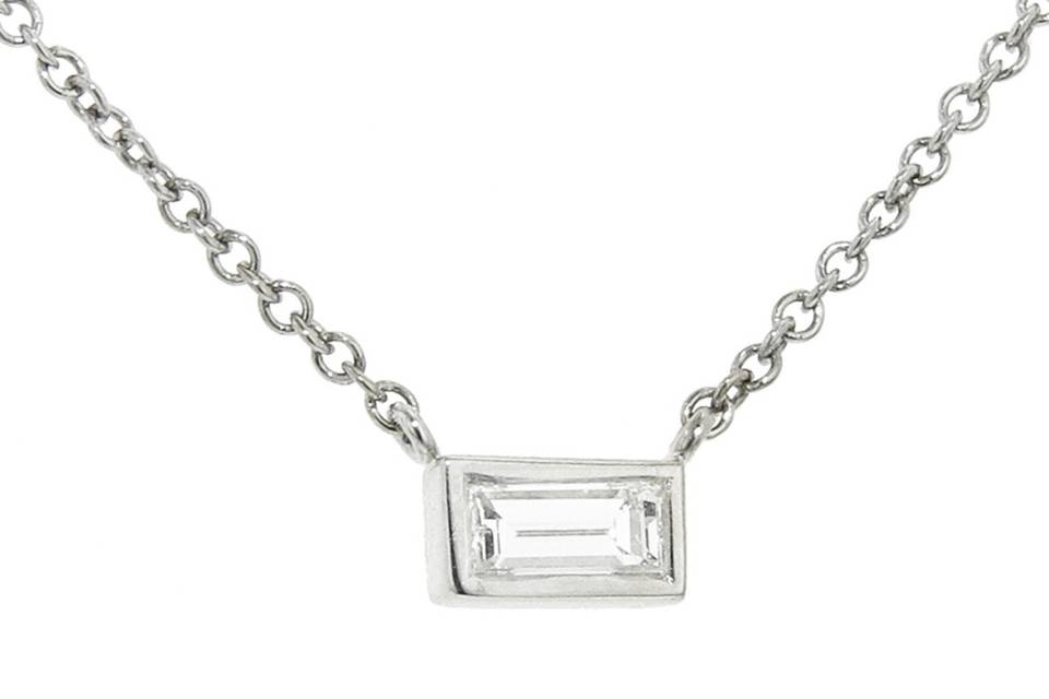 This dainty necklace from Finn is a small bezel set baguette diamond pendant cast in 18 karat white gold. It is suspended from a fine 16