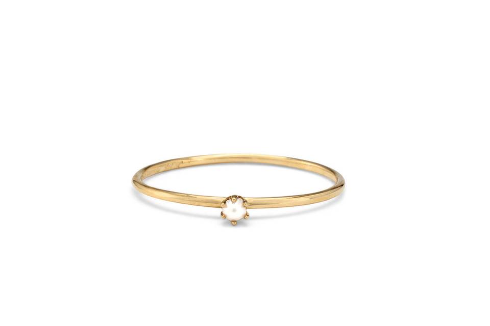 Each ring from designer Satomi Kawakita is handmade with impeccable precision. This thin, simple 18 karat yellow gold band features a tiny prong set pearl center. It has a lovely matte finish and looks lovely stacked or worn alone