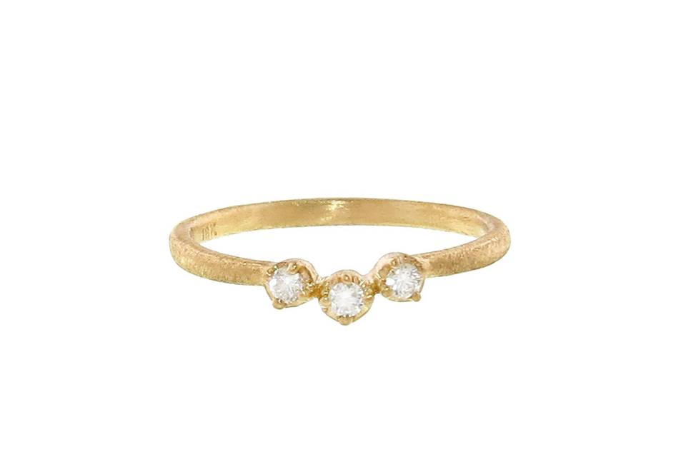 This gorgeous stacking ring from Yasuko Azuma is detailed by hand in 18 karat yellow gold with a lovely matte finish. It features a triplet of prong set diamonds that offer a slight curve for stacking purposes and is finished with a textured yellow gold band.