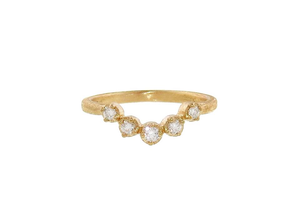 This gorgeous stacking ring from Yasuko Azuma is detailed by hand in 18 karat yellow gold with a lovely matte finish. It features five prong set diamonds that offer a slight curve for stacking purposes and is finished with a textured yellow gold band.