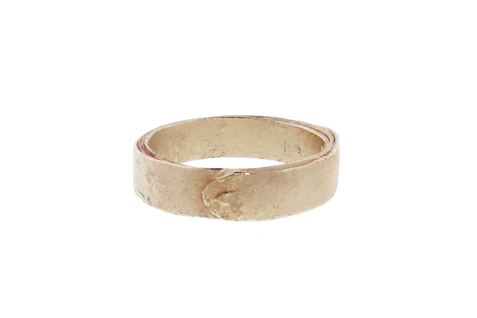 Solid with lovey texture, this band from Ruth Tomlinson is detailed in 14 karat yellow gold. It is made up of a thin piece of gold wrapped several times that leaves the edges on each side beautifully imperfect. The band stands 3/16
