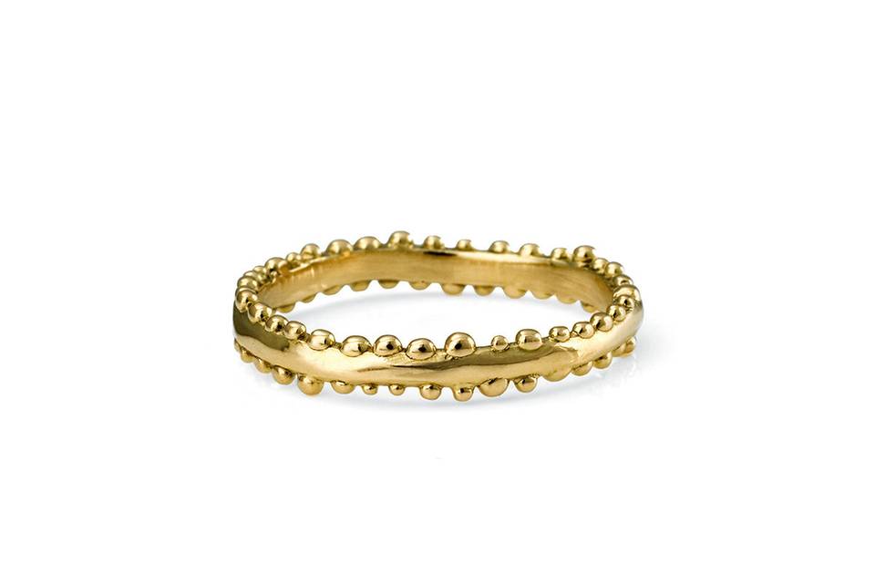 The handcrafted touches are nonstop on this ring from designer Satomi Kawakita. The 18 karat yellow gold band's organic feel is brought to life with each little gold bead placed along the edges. The beads go all the way around.