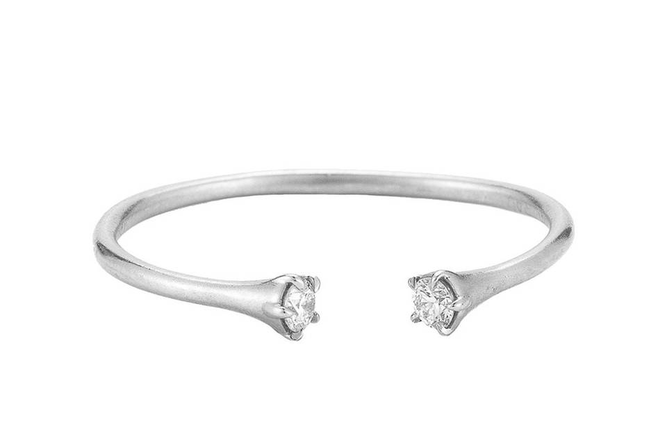 This dainty stacking ring from jewelry designer Jade Trau is composed of 14 karat white gold with an open center and diamond detail on either end. It looks perfect stacked with other bands and we currently have a size 6 1/2 or 7 available.