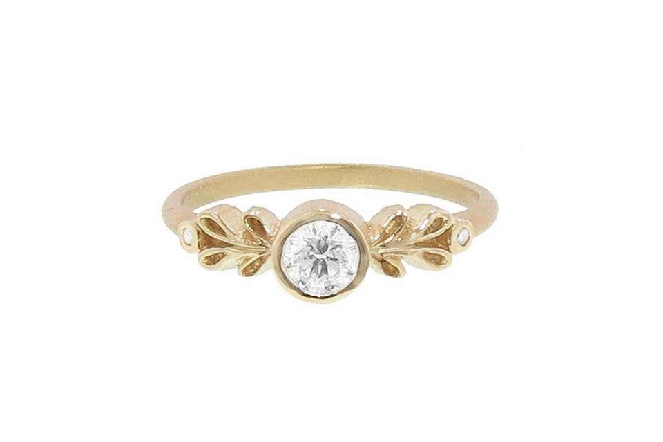 This Marina Solitaire Ring by designer Megan Thorne has a bezel set diamond center with a carat weight of .25cts and beautiful petal detailing on either side. In 18 karat yellow gold, this ring would look great worn alone or paired with Megan's Marina Guard Band.