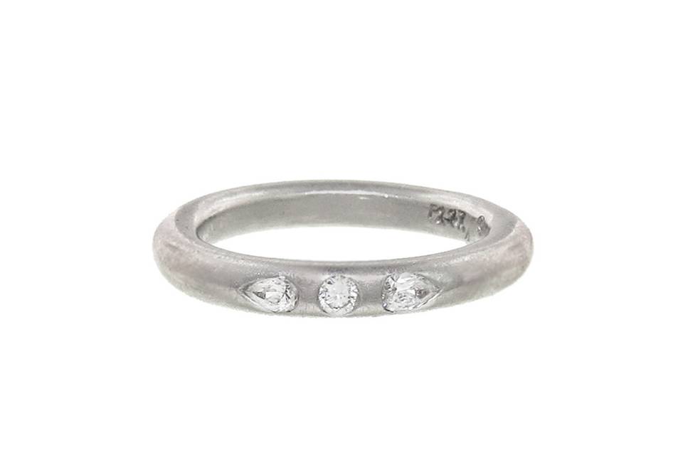 This platinum band from Cathy Waterman unites a classic design with a modern twist. The band is detailed by hand and features two bezel set pear diamonds that rest on either side of a tiny round diamond. Together the diamonds total .23 carats. This ring is great to wear alone or with Cathy's other stunning solitaire bands.