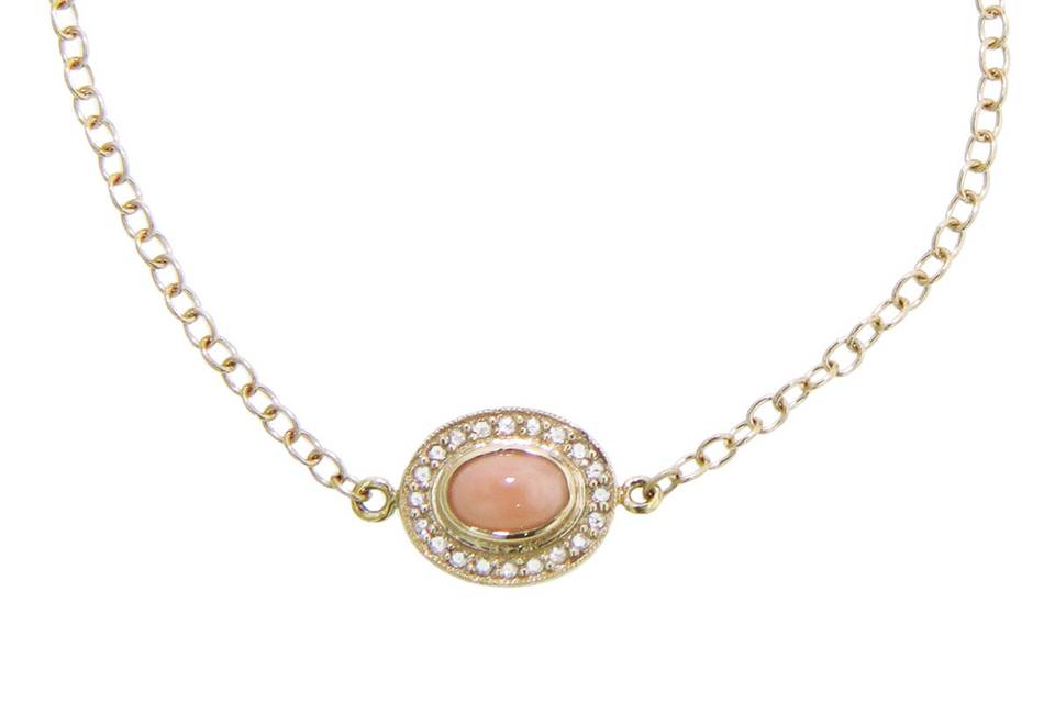 This delicate bracelet from Andrea Fohrman is detailed in 18 karat yellow gold, an oval pale coral stone framed in rose cut diamonds that is placed in the center of the bracelet. Open link chaining rests on either side of the bracelet, creating a total length of 6 3/4