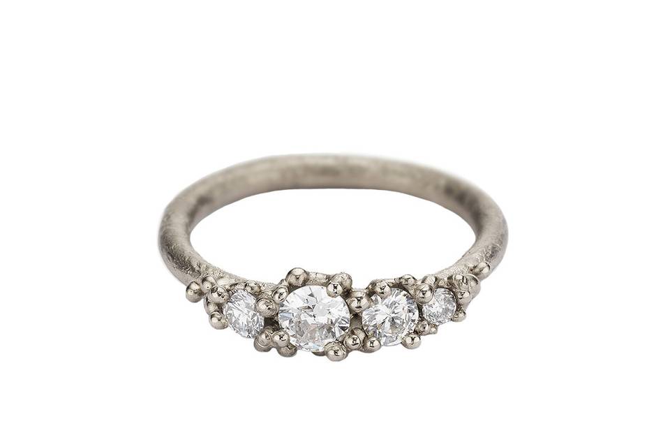This stunning handmade Four Stone White Diamond Ring from Ruth Tomlinson has an asymmetric row of four antique cut white diamonds, totaling .48 carats. Set in 18 karat white gold, with granule details surrounding the stones and a lightly textured band.