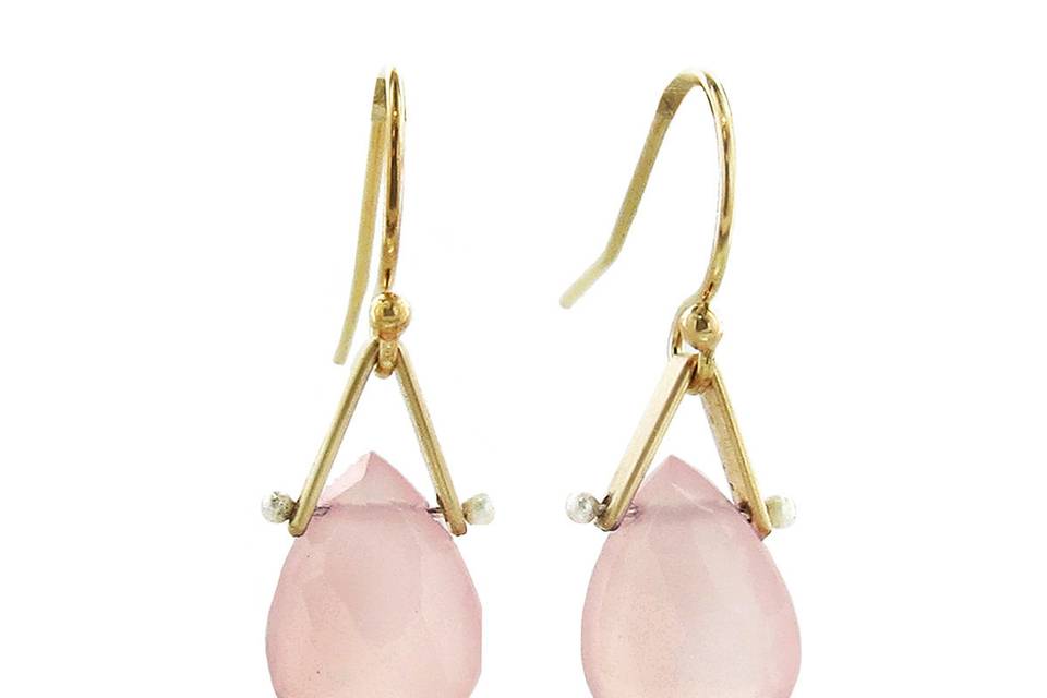 Soften and frame your face with these gorgeous earrings from LULU Designs. Crafted in 14 karat yellow gold these earring feature a pink chalcedony teardrop that hangs from a fine gold stirrup detailed in white pearls. These earrings measure 5/8