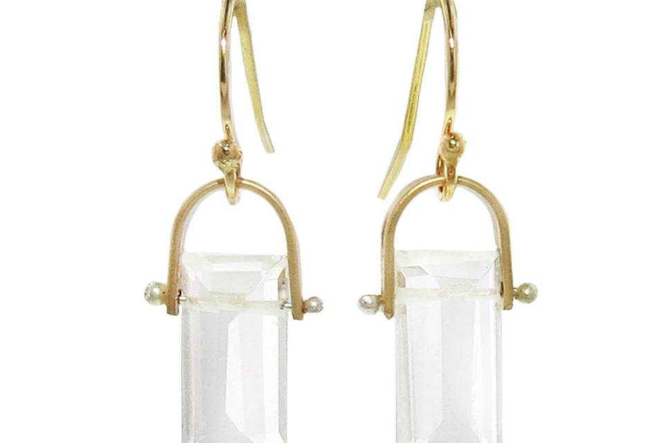 This staple earring from LULU Designs is a must-have for your everyday looks. These mini earrings feature 14 karat yellow gold-filled stirrups holding bright crystal quartz drops. The crystal quartz hangs from a fine gold bar that connects to the stirrups and is fastened with pearl detailing. They measure 5/8