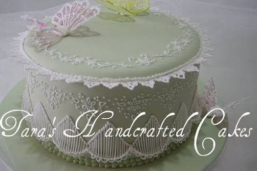 Fondant covered cake with intricate royal icing piped lace points, string work, butterflies and other design details.