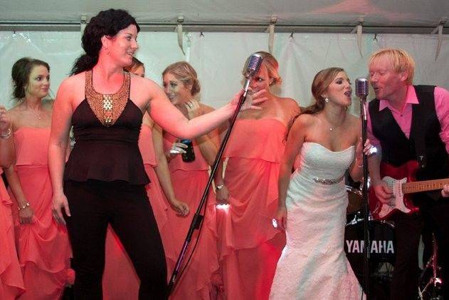 The bride and her bridesmaids singing with the band