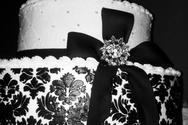 This three tiered butter cream  cake has a black damask pattern and fondant bow with a crystal brooch. LOVELY