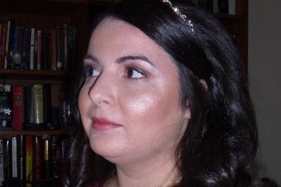 Hair is down with curls and delicate rhinestone headband.  Make-up done with warm colors.