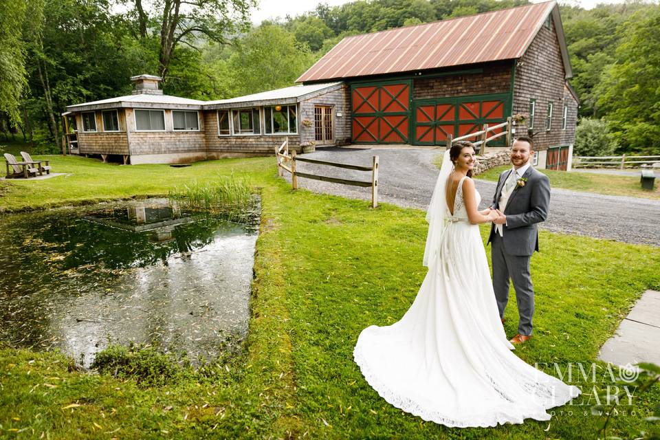 A joyful bride and groom surrounded by bridesmaids in front of one of our rustic wedding barns.