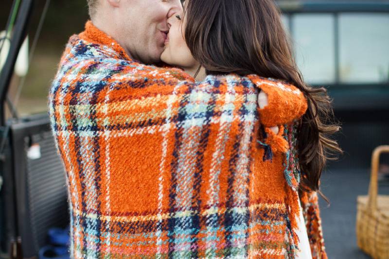 Fishing engagement session, couple wrapped in blanket on truck tailgate