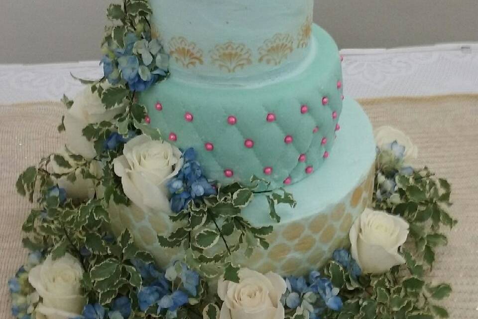 White roses with blue delphinium accent this custom wedding cake