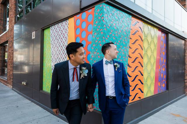 Two grooms against a wall of color