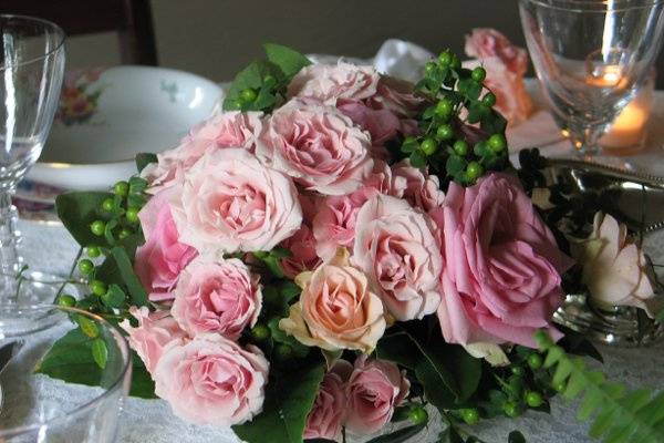 pink roses, green hypericum and petit jasmine vine make and elegant centerpiece in a sivler bowl.