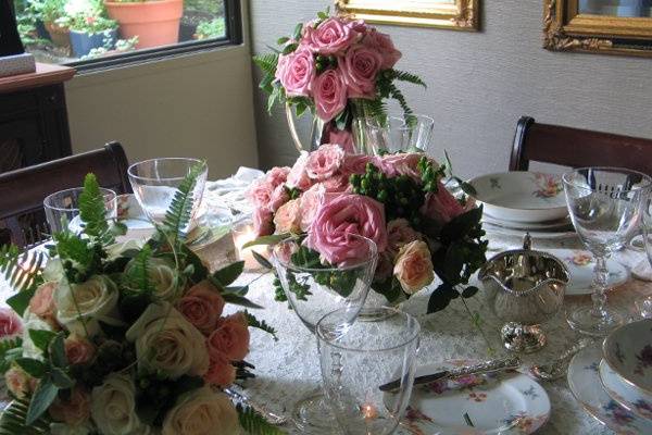 Bridal bouquet, attnedant's bouquet, centerpiece and votive candles accent an elegant formal table setting.