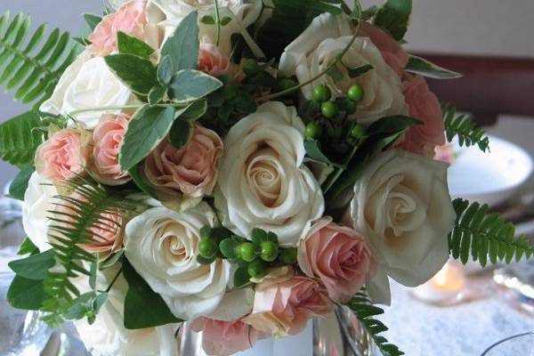 Bridal bouquet with ivory and chamgagne toned roses, green hypericum, fern, ornamental bay, and Vinca vines.
