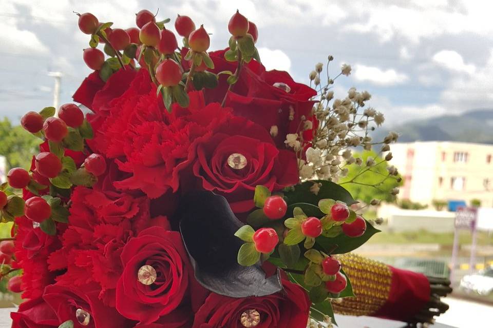 Shades of red with lush red roses, calla lillies, hypercurium berries, & babies breath wrapped, with merlot satin ribbon & gold bling