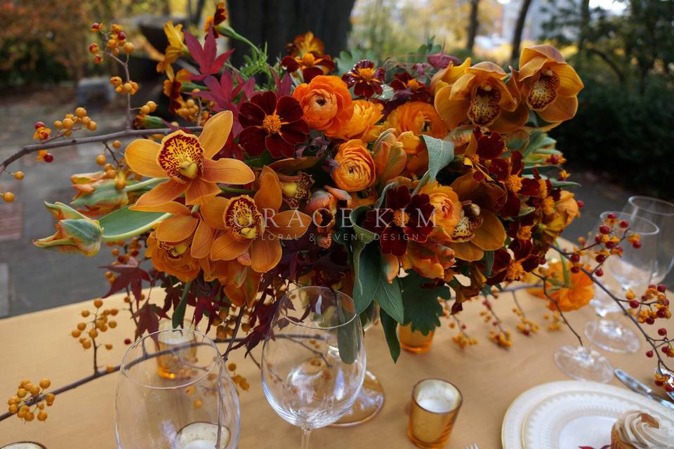 Grace Kim Floral & Event Design- orange & gold centerpiece: cymbidium orchids, marigolds, weber tulips, ranunculus, sage, japanese maple branches, bittersweet branches