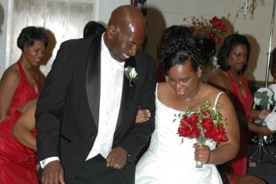 The O'Neal's start their lives together by jumping a broom decorated in their wedding colors of red and cream.