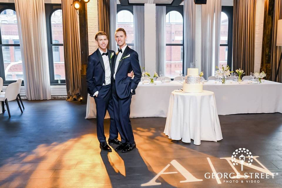 Grooms pose with wedding cake