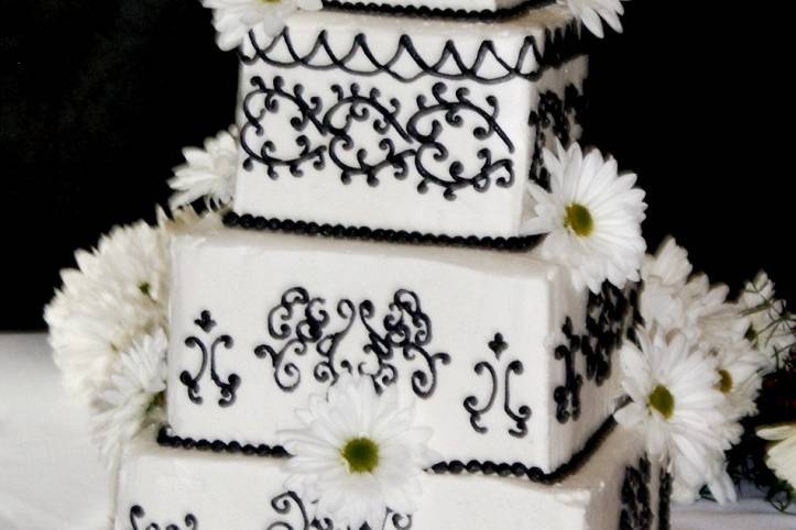 Intricate hand-piped buttercream design on buttercream covered cake.  Silk flowers complete the cake.