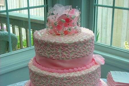 Stacked wedding cake adorned with pink satin ribbon.