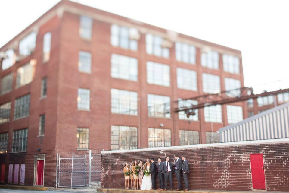 Newlyweds and their guests by the brick wall